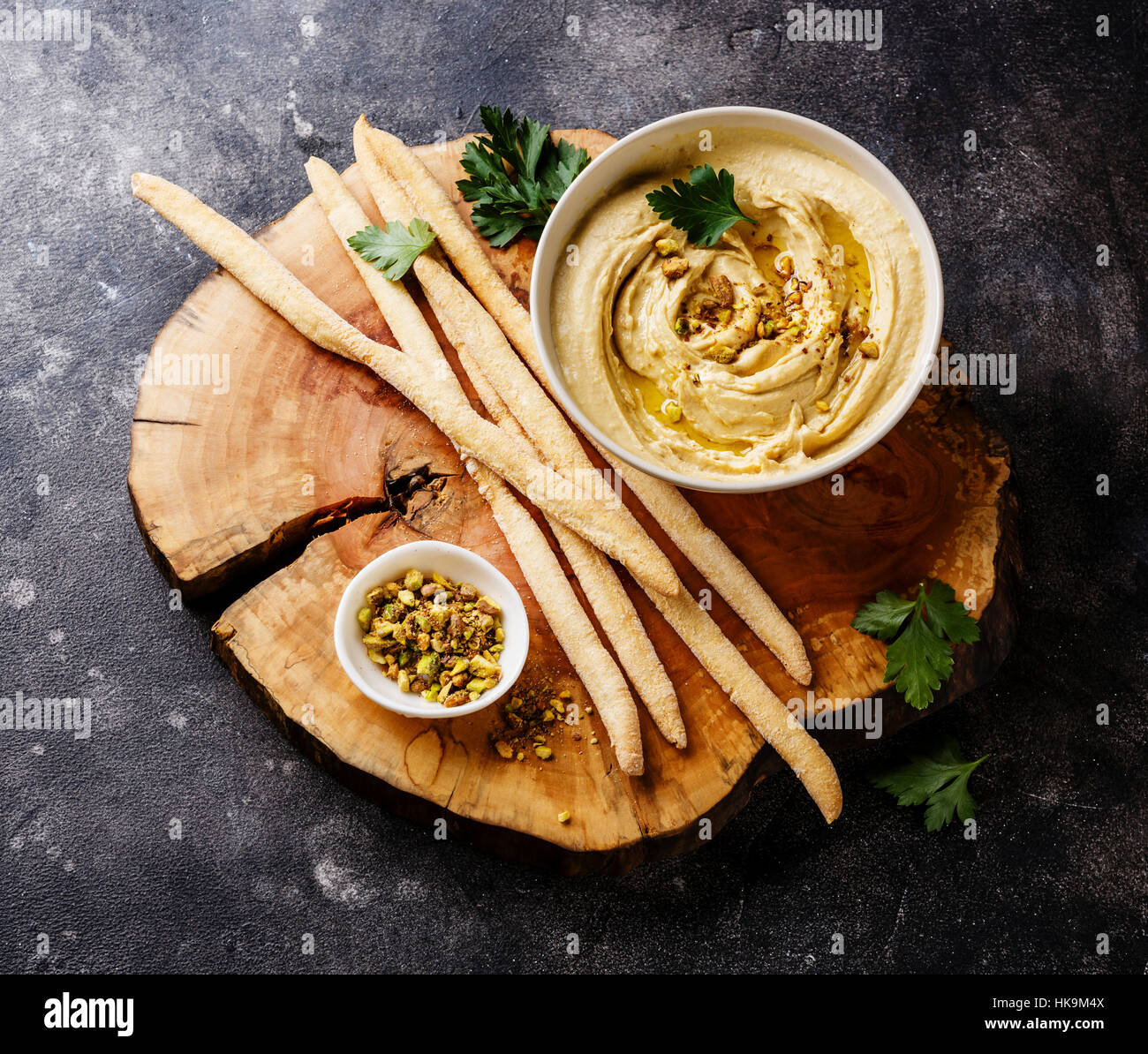 Homemade hummus with pistachios and bread sticks on black stone background Stock Photo