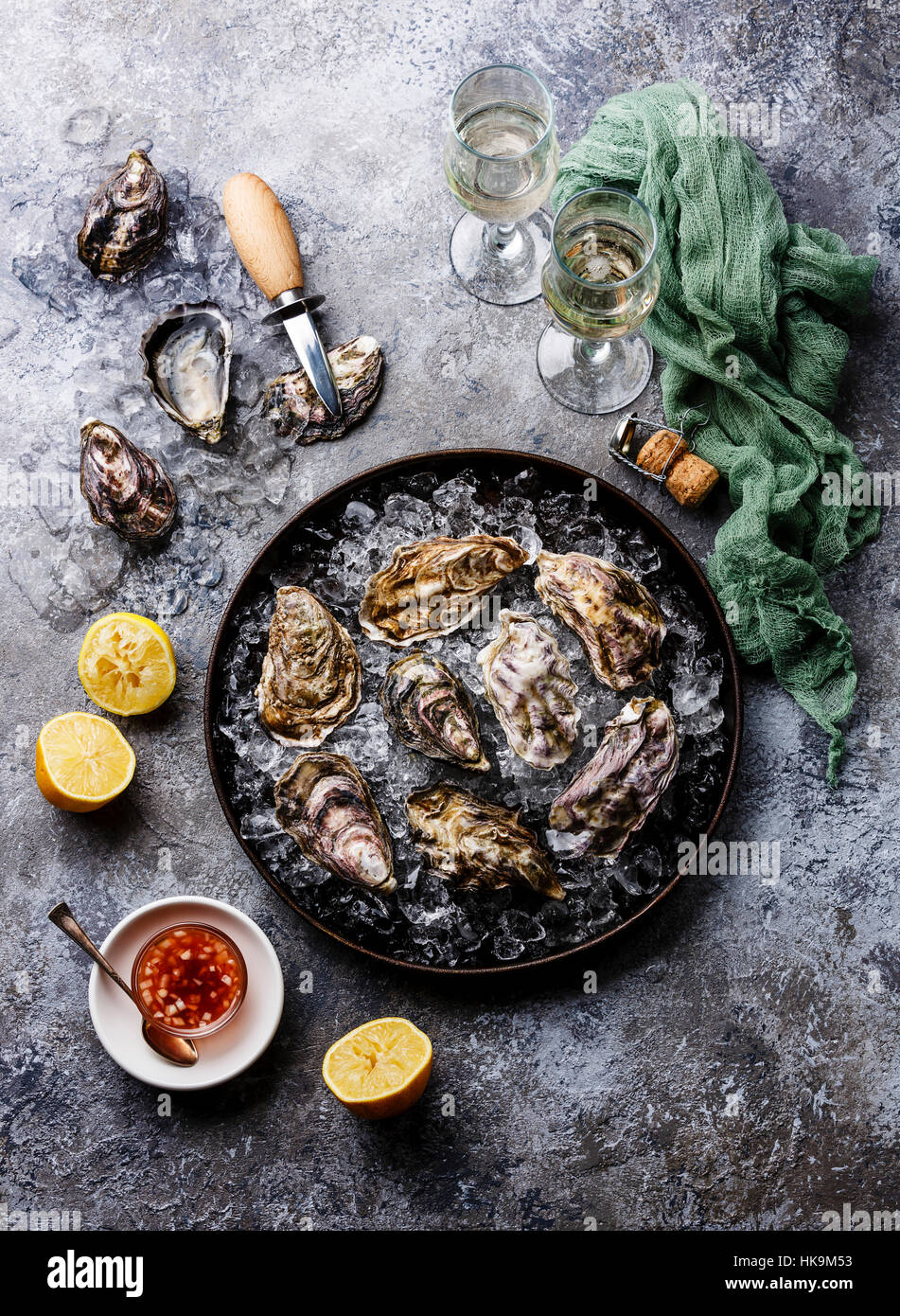 Oysters in plate with spicy sauce and champagne on stone texture background Stock Photo