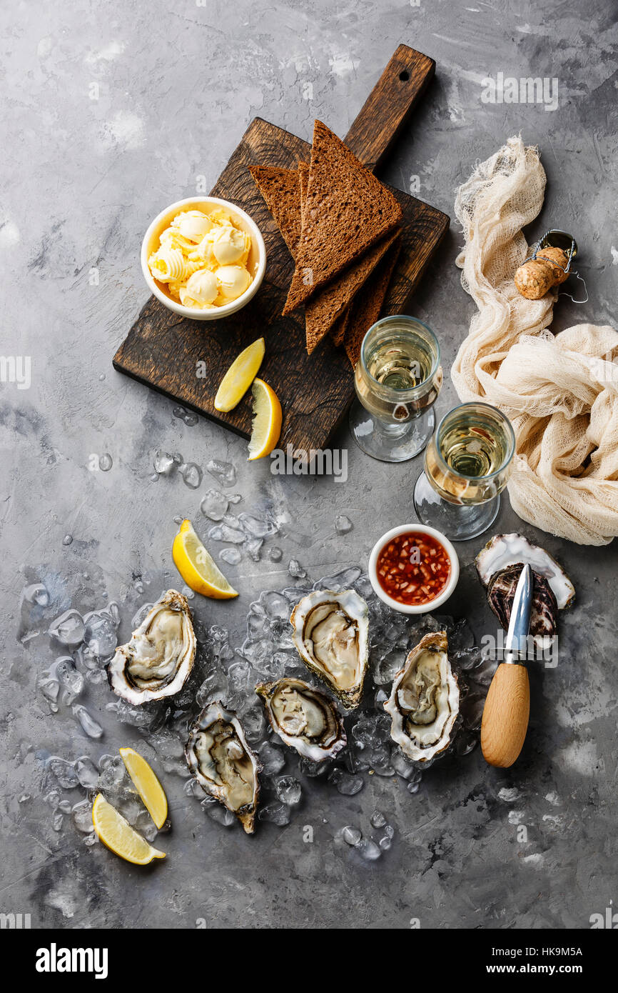 Open Oysters with bread and butter and champagne on gray concrete texture background Stock Photo