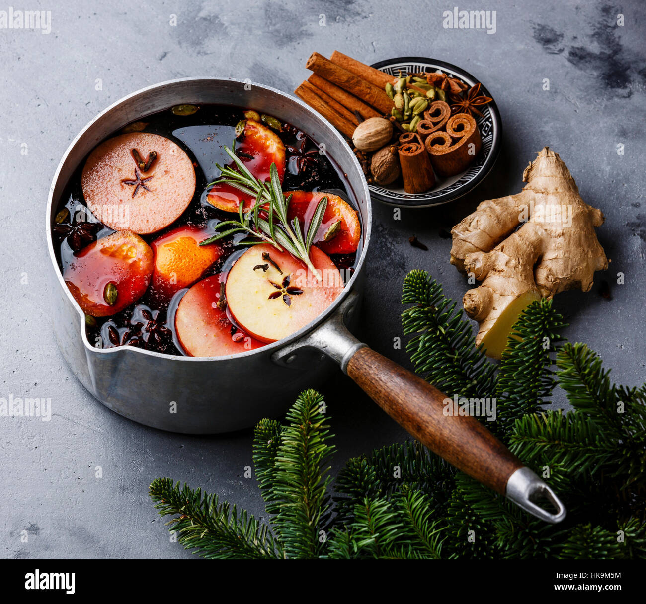 Mulled wine hot drink with citrus, apple and spices in aluminum casserole on concrete background Stock Photo