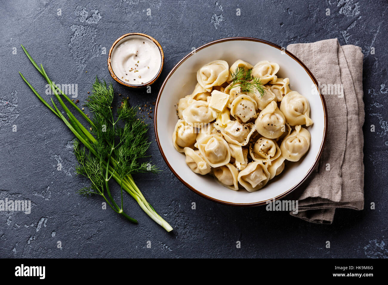 Russian pelmeni meat Dumplings with sauce sour cream and greens in bowl