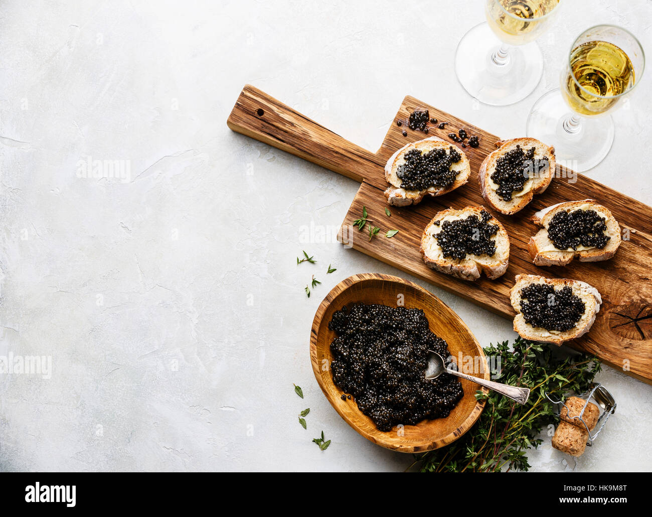 Sturgeon black caviar in wooden bowl, sandwiches and champagne on white background copy space Stock Photo