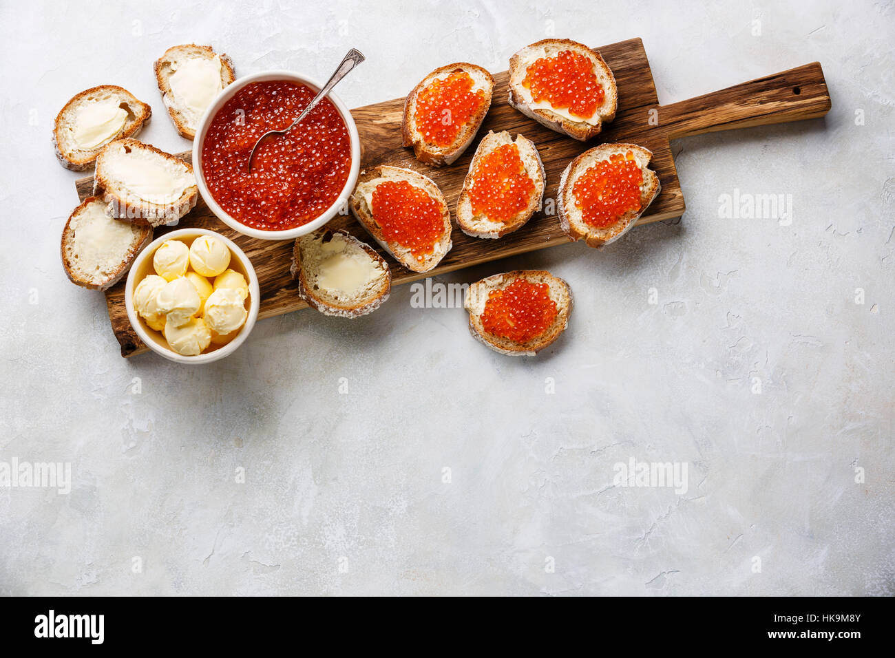 Salmon red caviar in bowl and Sandwiches on wooden cutting board on white background copy space Stock Photo