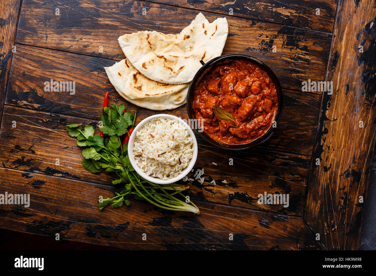 Chicken tikka masala spicy curry meat food in cast iron pot with rice and fresh naan bread on wooden background Stock Photo