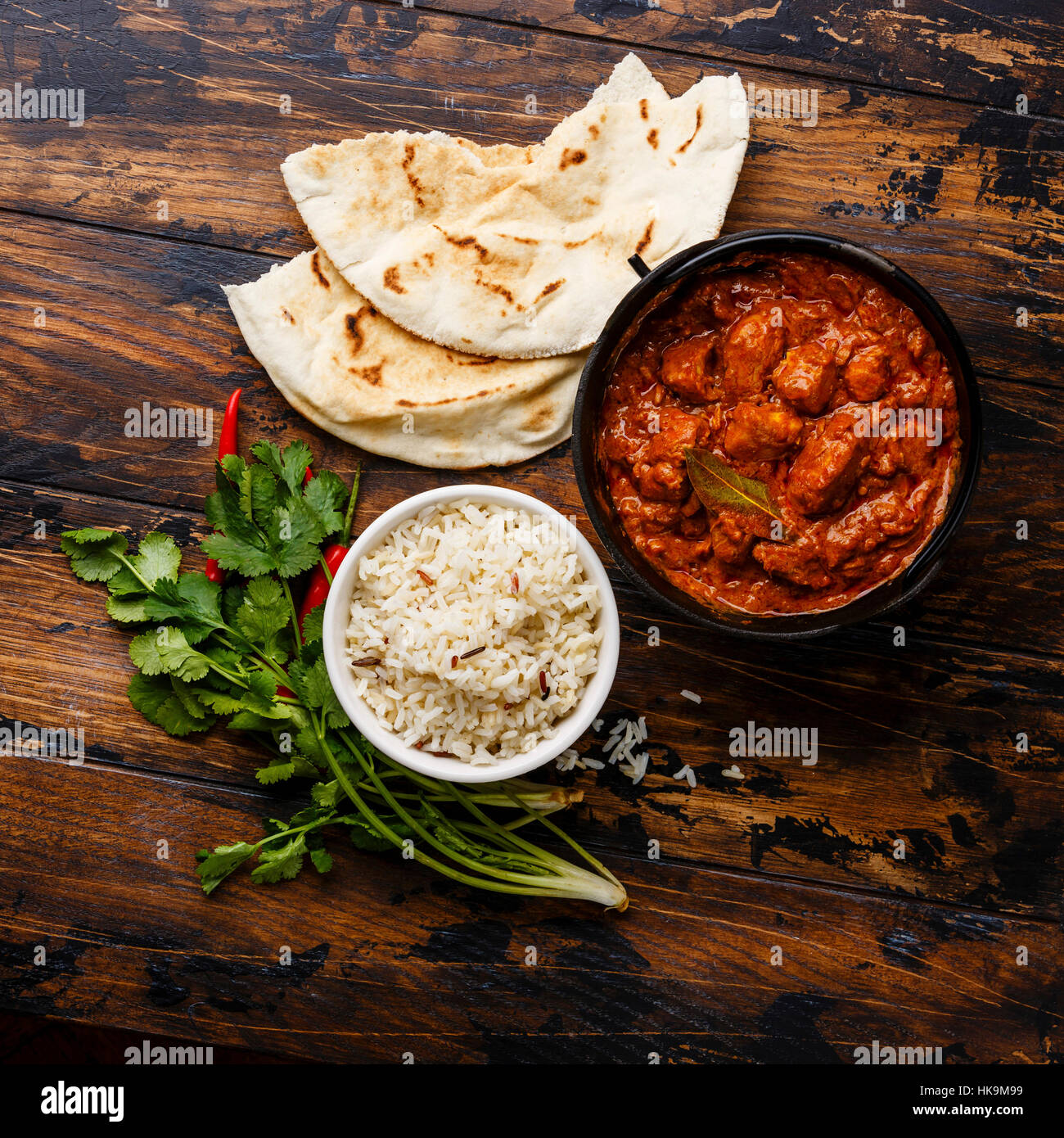 Chicken tikka masala spicy curry meat food in cast iron pot with rice and fresh naan bread on wooden background Stock Photo