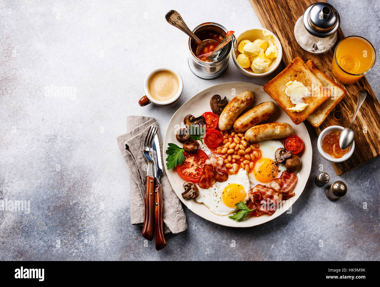 Full English breakfast with fried eggs, sausages, bacon, beans, toasts and coffee on copy space background Stock Photo