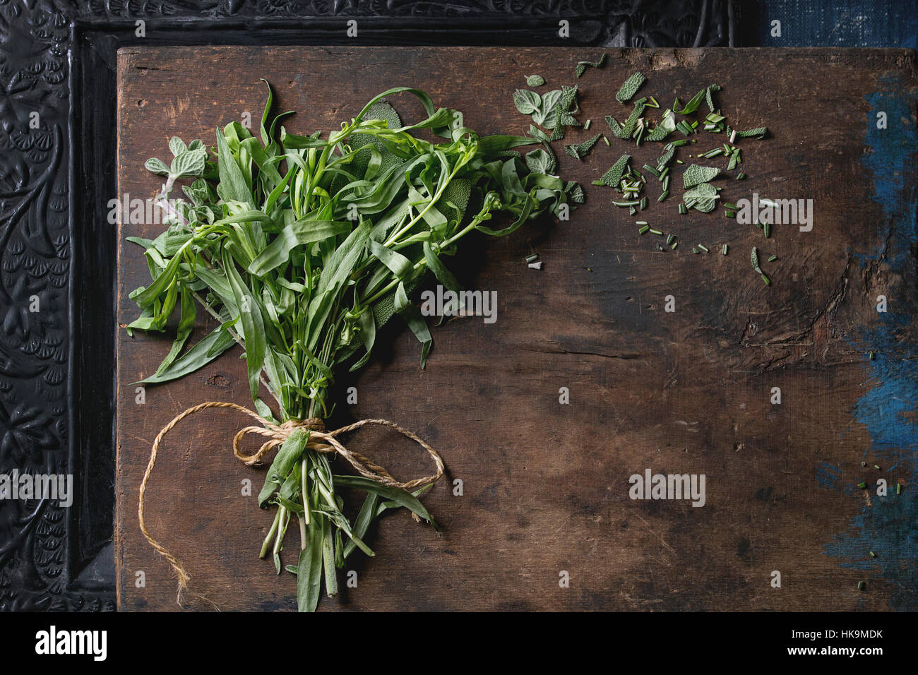 Bundle of fresh and cutting Italian herbs rosemary, oregano and sage over old dark wooden and black ornate background. Top view with copy space Stock Photo