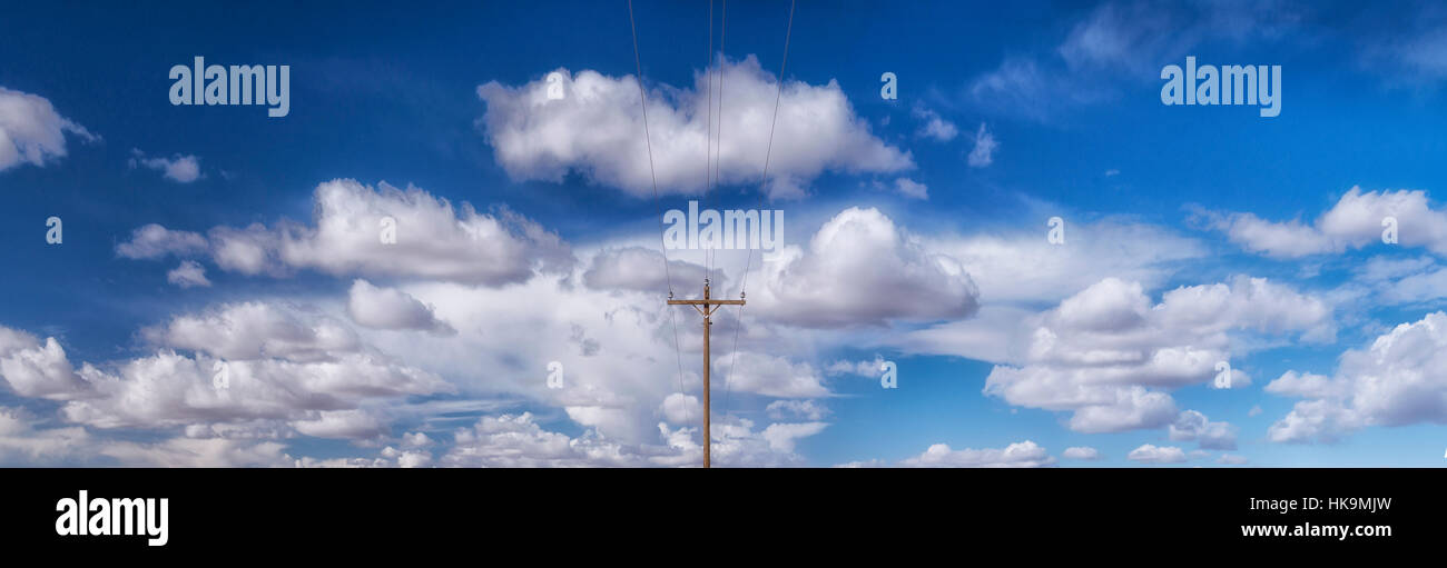 A colorful,panoramic,surrealist image of a lone phone pole and cloud formations in the desert sky near Amargosa Dunes in Nevada Stock Photo