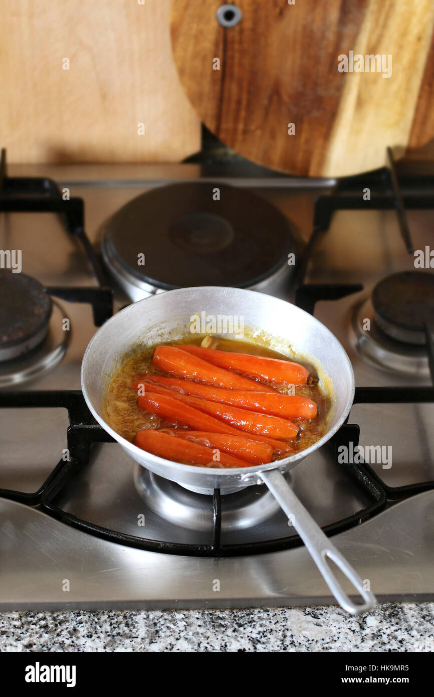 Honey glazed Carrots in pan simmering in freshly squeezed orange juice to glaze Stock Photo
