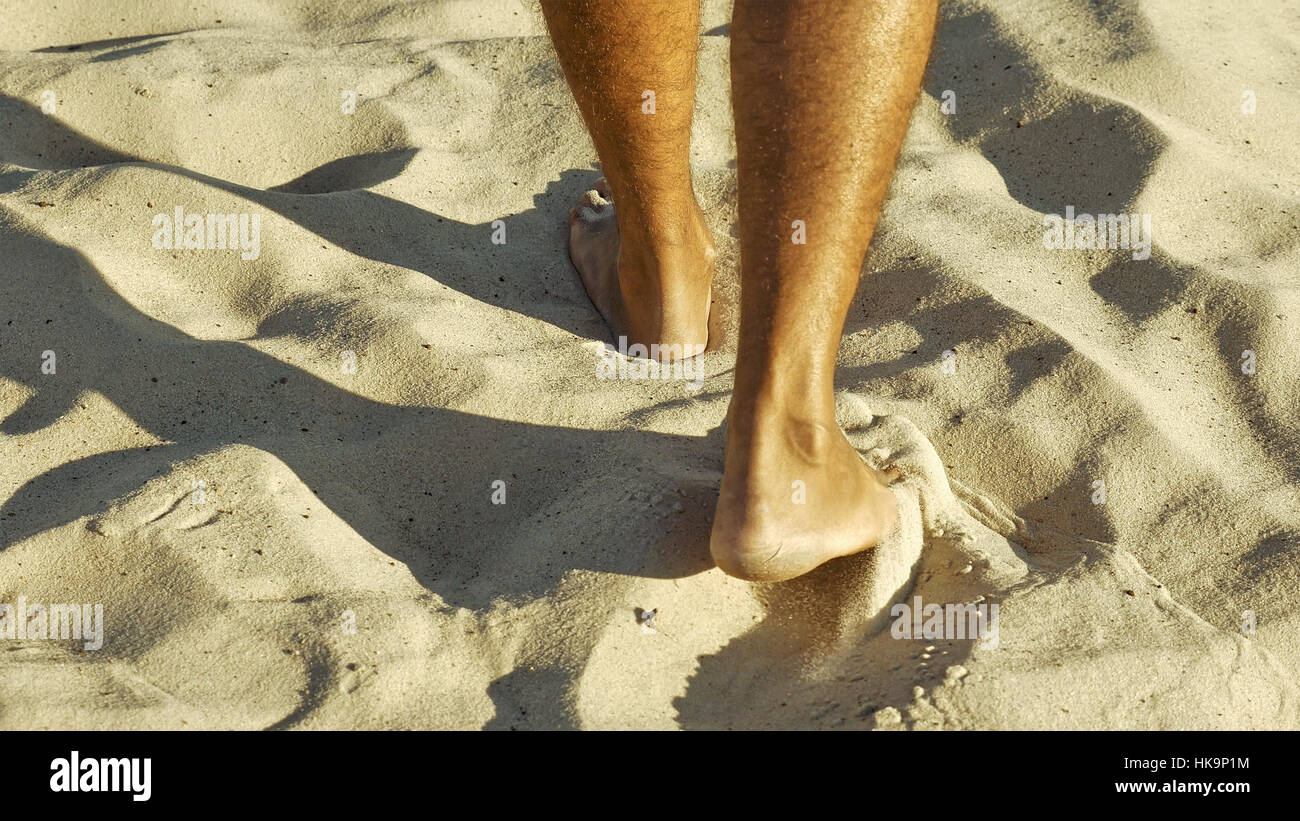 Male feet walking on sand Stock Photo