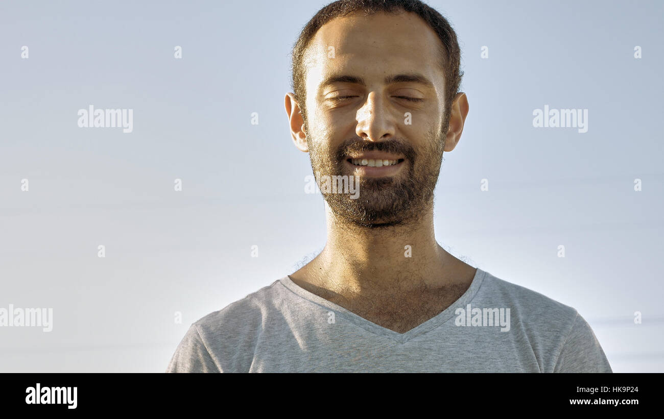 Cheerful man smiles with eyes closed Stock Photo