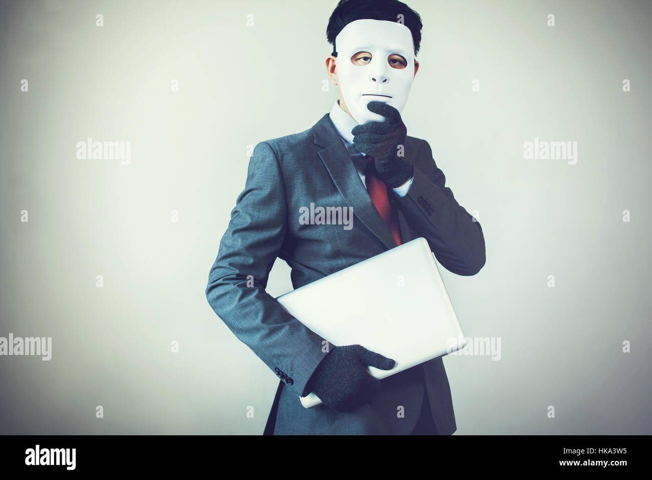 Business man in white mask wearing gloves and stealing computer and