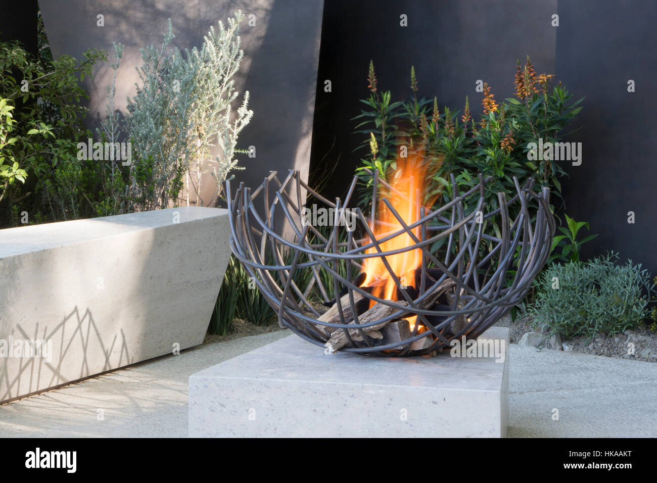 A modern stone patio with bench seat and outdoor firepit fire pit The