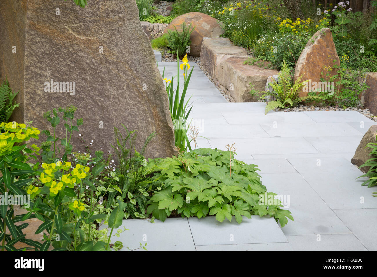 Stone paving garden path in a contemporary garden with stone boulders for raised beds The M&G Garden,Cleve West, Chelsea Flower Show, London  UK Stock Photo