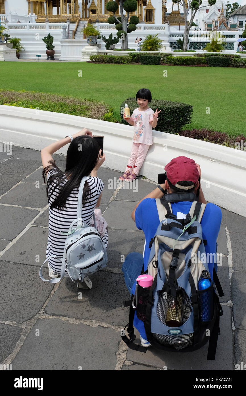 Proud tourist parents taking photos of daughter making a model face. Photo touristic mania Stock Photo