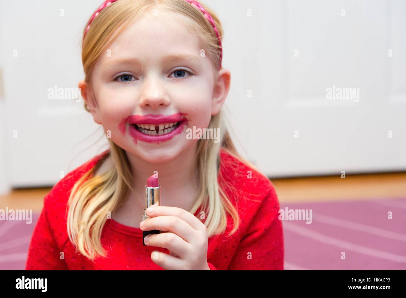 adorable school age girl putting on lipstick Stock Photo Alamy