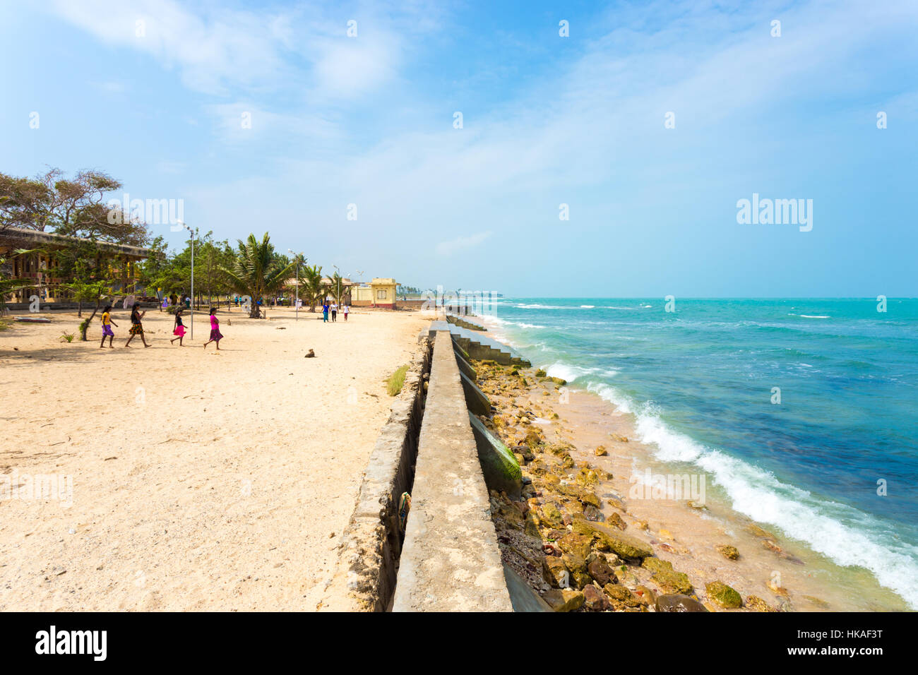 Tourists walking on the beach in view of the ocean adjacent to Keerimalai Hot Springs on a sunny day, northern coast of Jaffna Stock Photo
