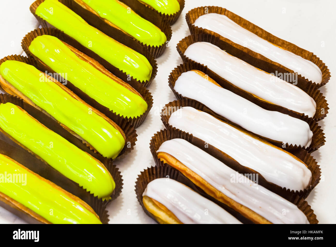 Rows of colorful eclairs, small, soft, log-shaped pastry filled with cream Stock Photo