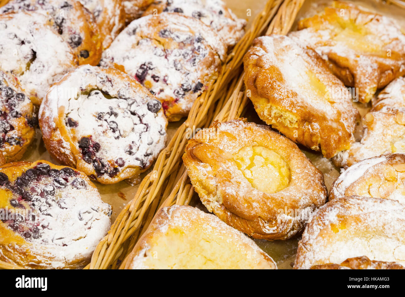 Sweet buns with berries and sugar powder lay on shelves of bakery shop Stock Photo