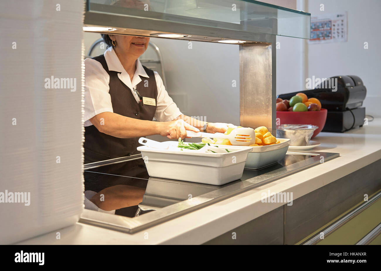 Canteen assistant preparing and serving food in a hospital Stock Photo