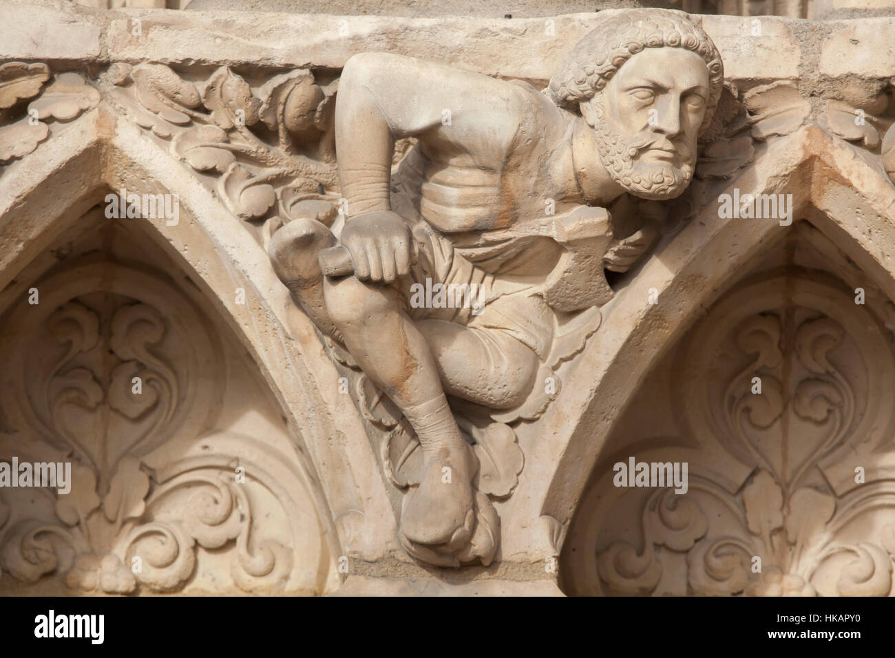 Man with an axe. Neo-Gothic statue on the main facade of the Notre-Dame Cathedral (Notre-Dame de Paris) in Paris, France. The damaged Gothic portal was restored by French architects Eugene Viollet-le-Duc and Jean-Baptiste Lassus in the 1840s. Stock Photo
