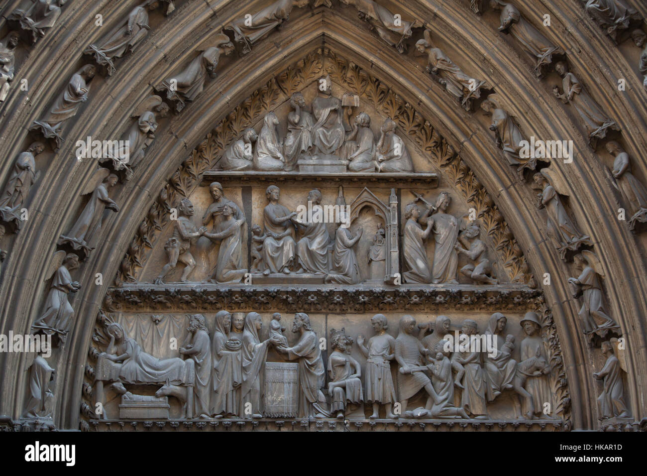 Gothic tympanum from circa 1250 on the northern facade of the Notre-Dame Cathedral (Notre-Dame de Paris) in Paris, France. Scenes from the early life of Jesus Christ (bottom row) and from the life of Saint Theophilus the Penitent who is said to have made a deal with the Devil (top row) are depicted in the relives. Stock Photo