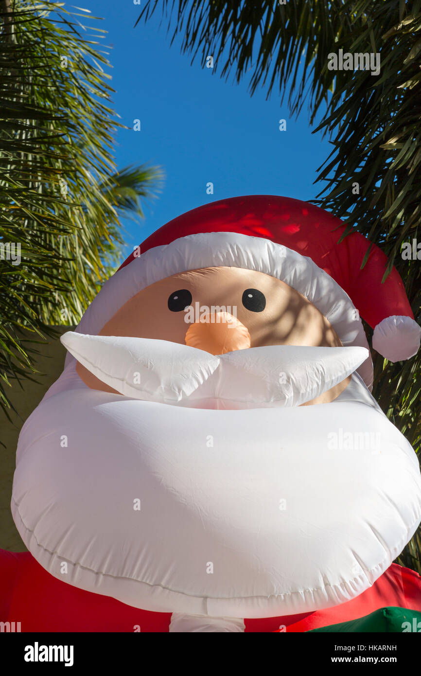 GIANT INFLATABLE SANTA CLAUS IN FRONT OF PALM TREES IN RESIDENTIAL FRONT YARD MIAMI FLORIDA USA Stock Photo