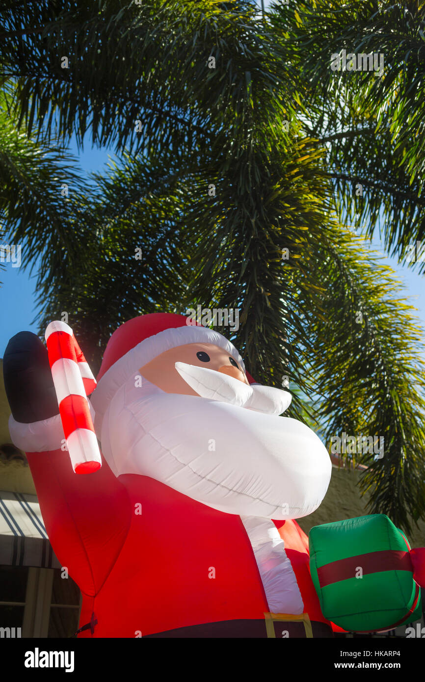 GIANT INFLATABLE SANTA CLAUS IN FRONT OF PALM TREES IN RESIDENTIAL