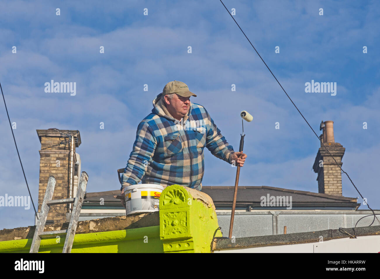 London, Lewisham   A painter and decorator pausing from his labours on a rooftop in Brockley Stock Photo