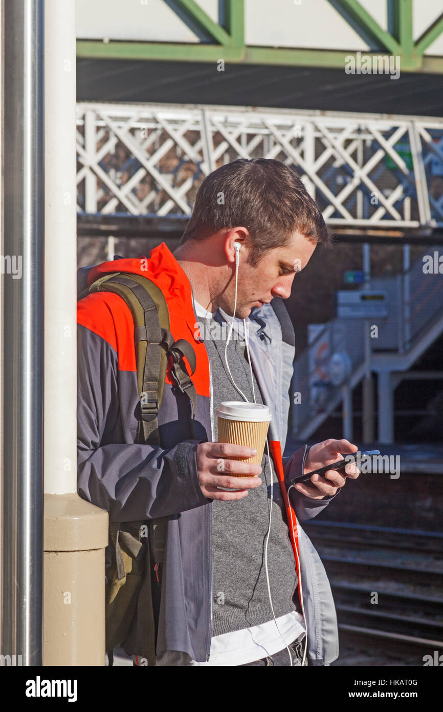 A commuter checking his i phone at Brockley railway station in Lewisham Stock Photo