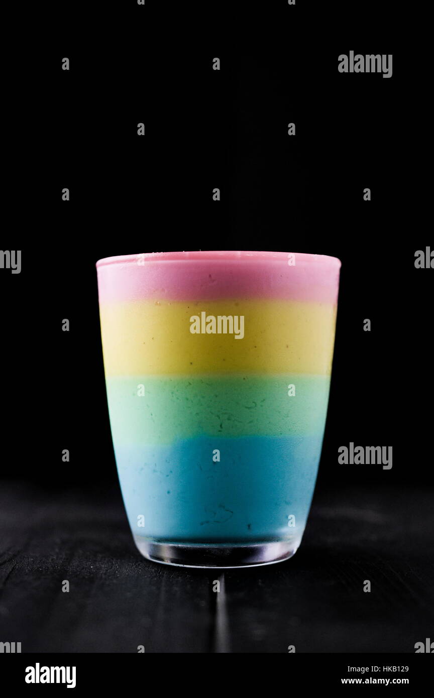 The taste of color rainbow pudding in glass on black. Layered different