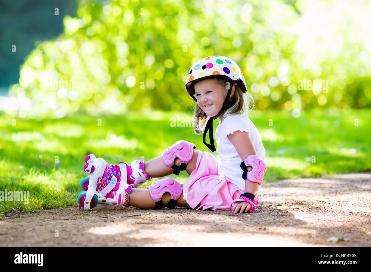 Girl and boy learn to roller skate in summer park. Children wearing