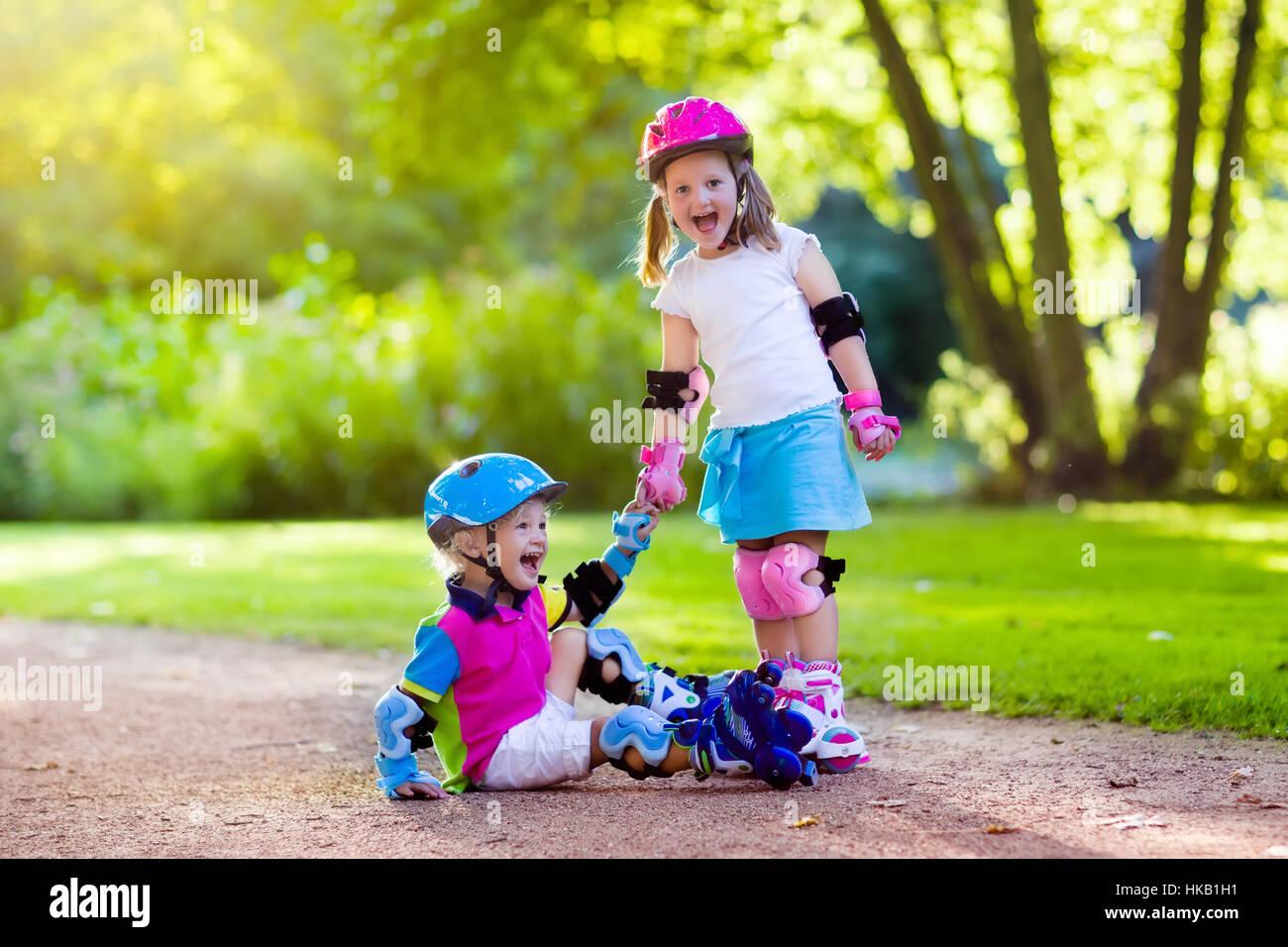 Girl and boy learn to roller skate in summer park. Children wearing