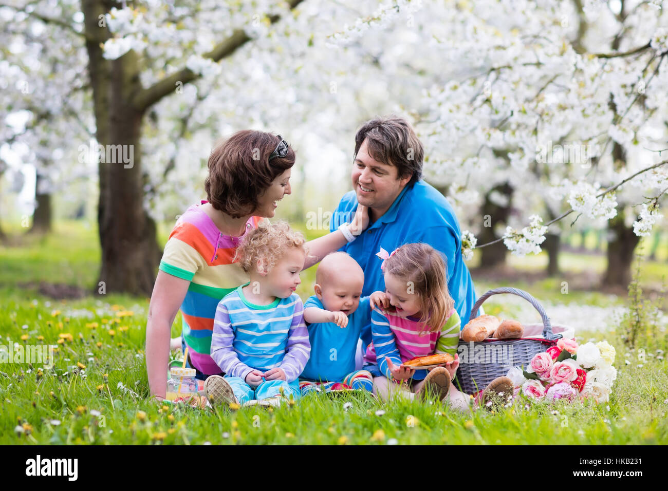 Big family with three little children eating lunch outdoors. Parents