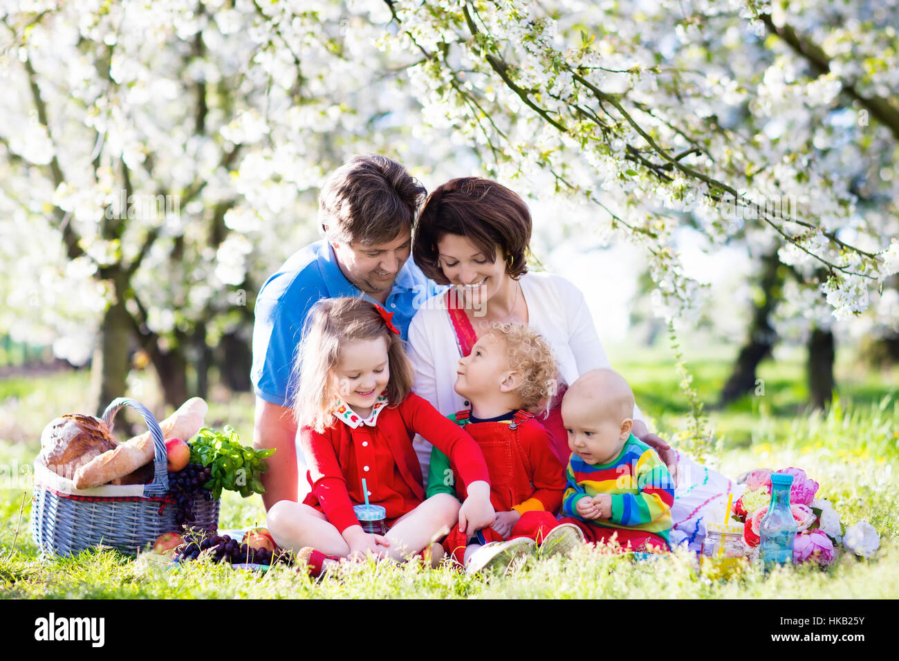 Big family with three little children eating lunch outdoors. Parents
