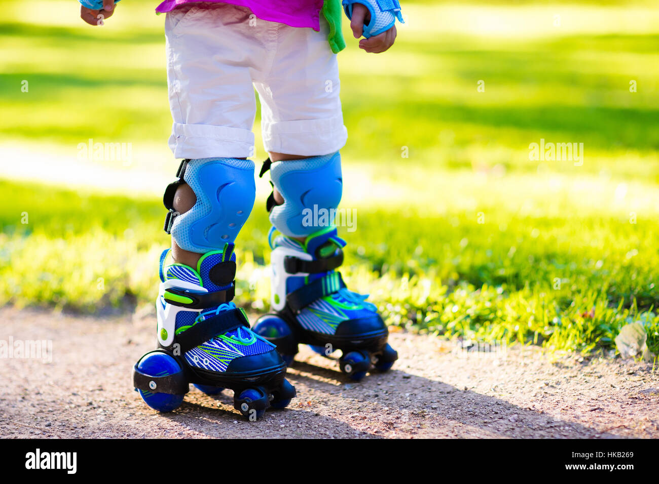 Girl and boy learn to roller skate in summer park. Children wearing