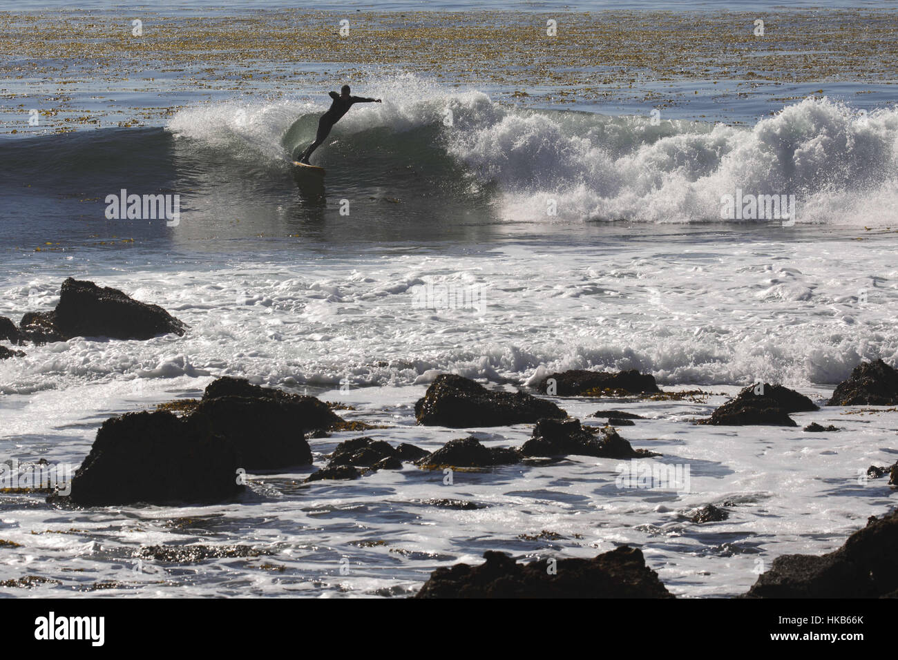 Palos Verdes Estates, CA, USA. 29th Nov, 2016. A man surfs as city contractors demolish a patio built by local surfers on the shoreline of the Pacific Ocean at Lunada Bay on Tuesday, November 29, 2016 in Palos Verdes Estates, Calif. The patio fort was a popular hangout of the Lunada Bay Boys and the process of tearing it down has become a flashpoint in the debate over surfing localism. © 2016 Patrick T. Fallon Credit: Patrick Fallon/ZUMA Wire/Alamy Live News Stock Photo