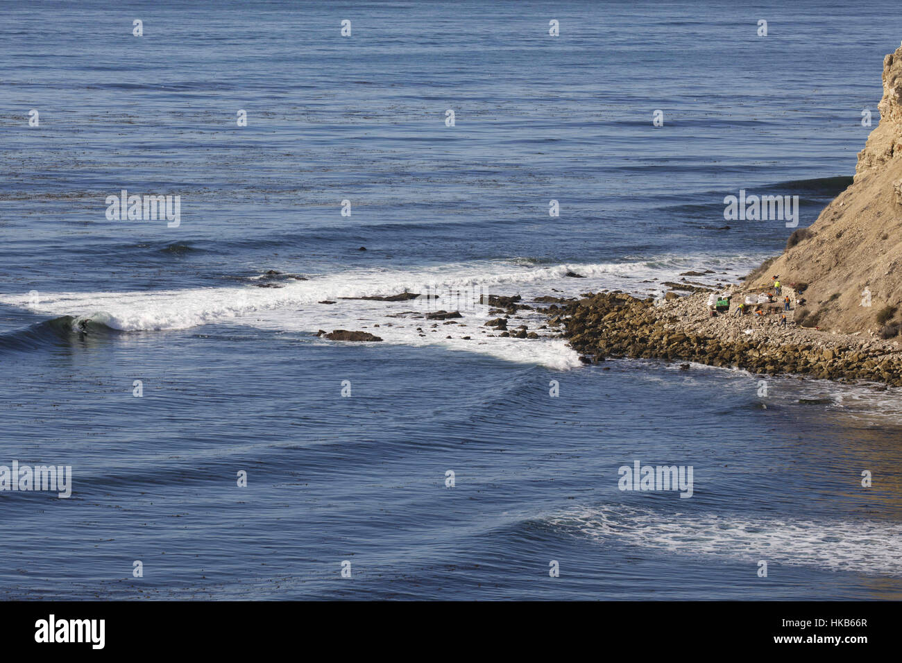November 29, 2016 - Palos Verdes Estates, CA, U.S. - A man surfs as city contractors demolish a patio built by local surfers on the shoreline of the Pacific Ocean at Lunada Bay on Tuesday, November 29, 2016 in Palos Verdes Estates, Calif. The patio fort was a popular hangout of the Lunada Bay Boys and the process of tearing it down has become a flashpoint in the debate over surfing localism. Â© 2016 Patrick T. Fallon (Credit Image: © Patrick Fallon via ZUMA Wire) Stock Photo
