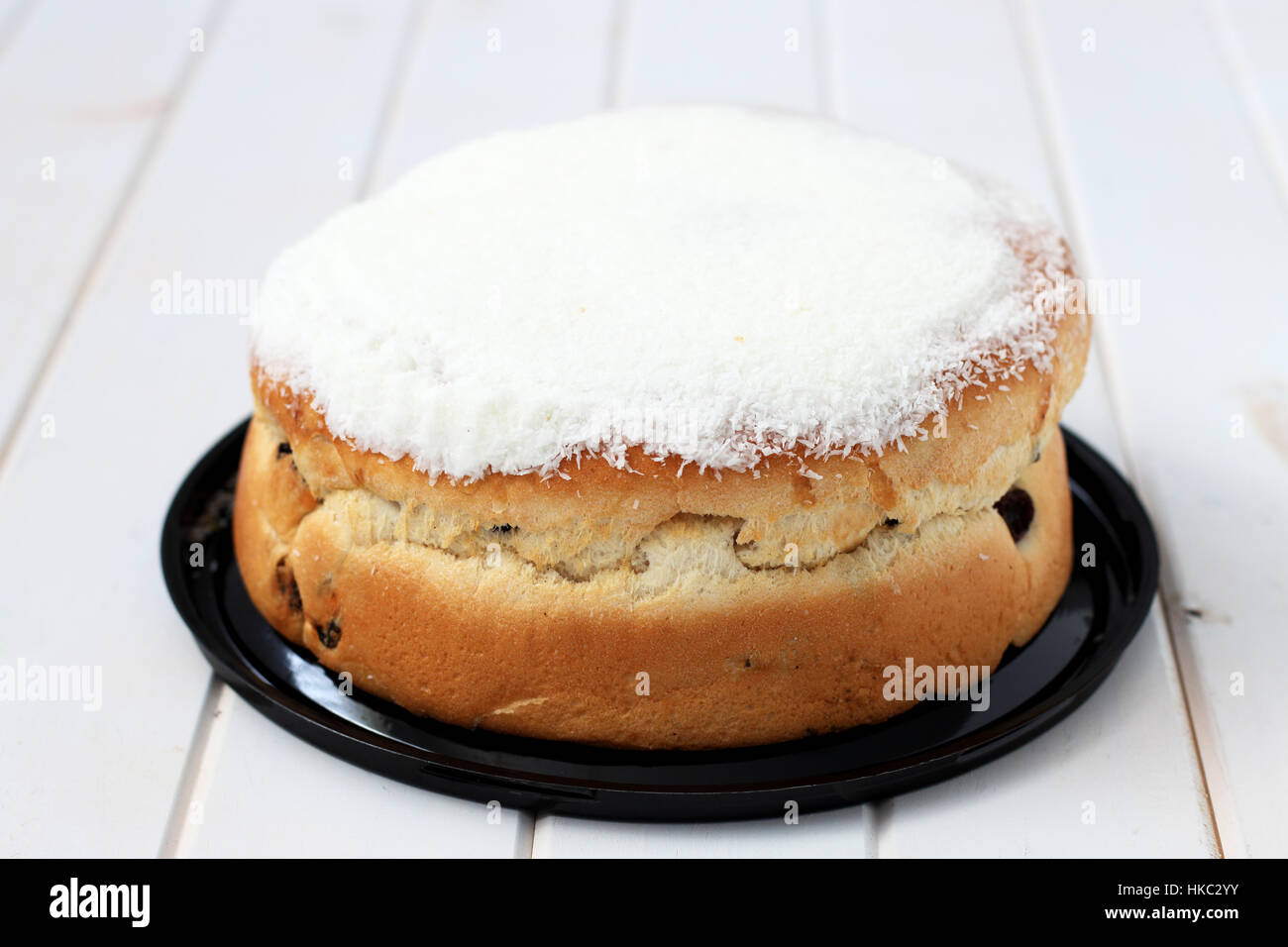 Boston Bun with coconut icing on white timber Stock Photo