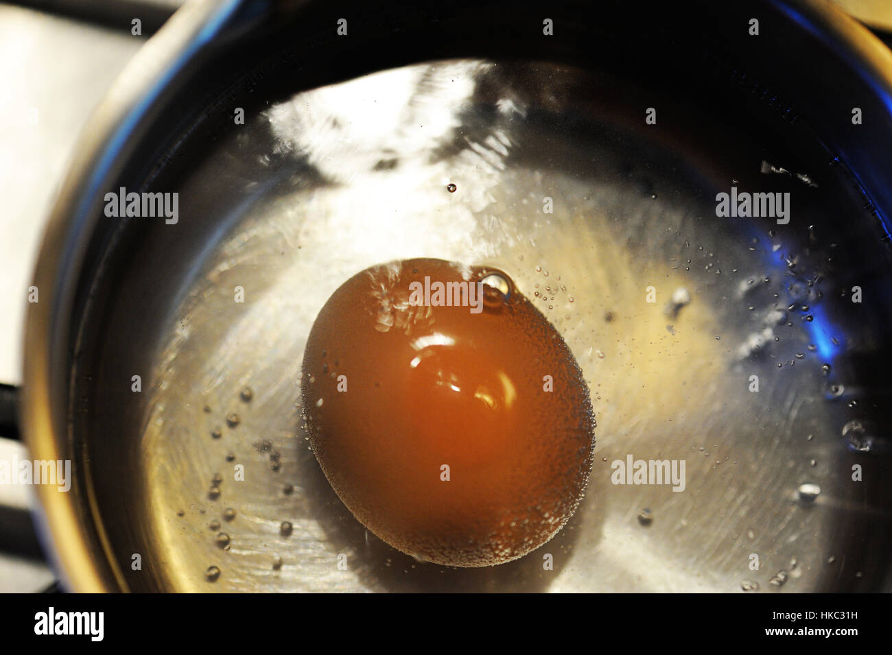 Brown egg starting to boil in a steel pot Stock Photo