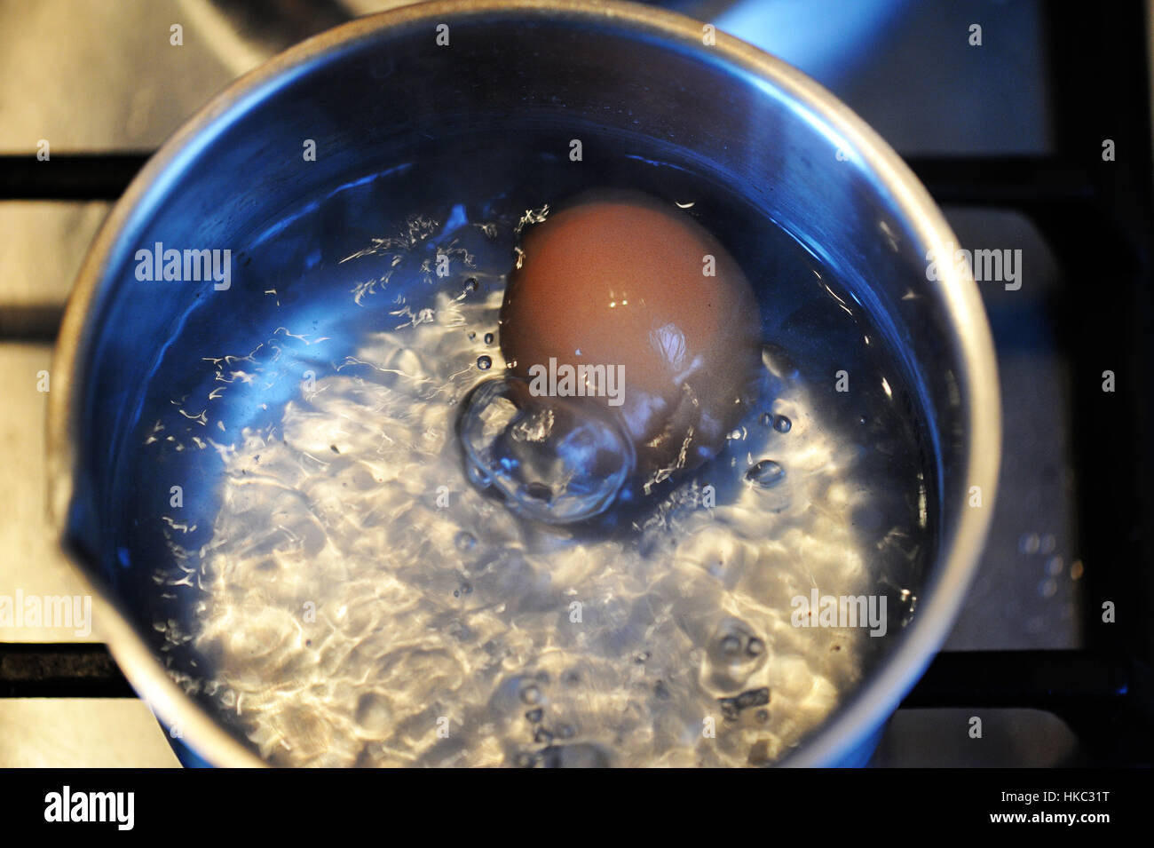 Egg starting to boil in a steel pot Stock Photo