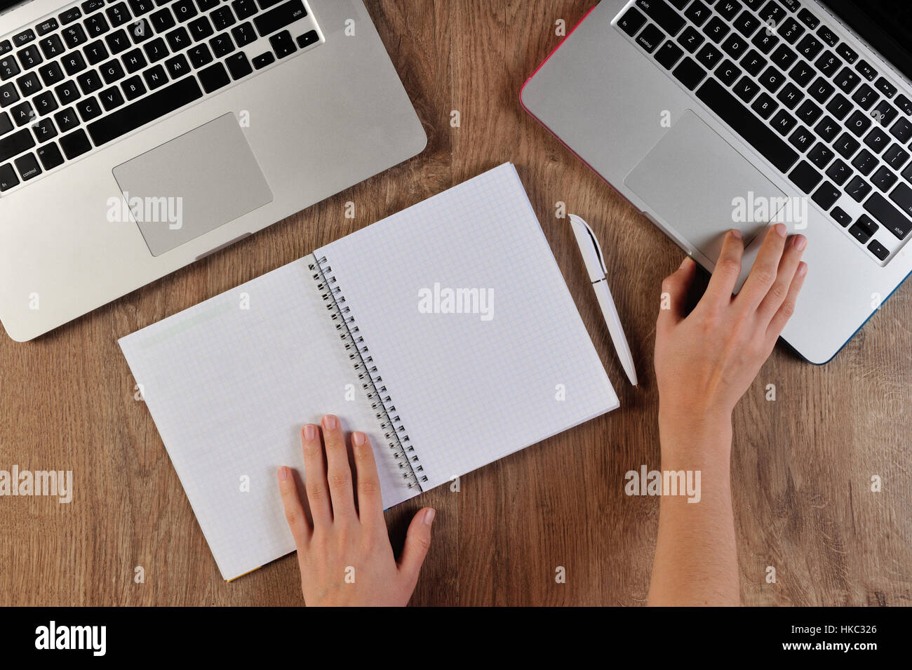 person writing in notebook infront of two laptops Stock Photo - Alamy