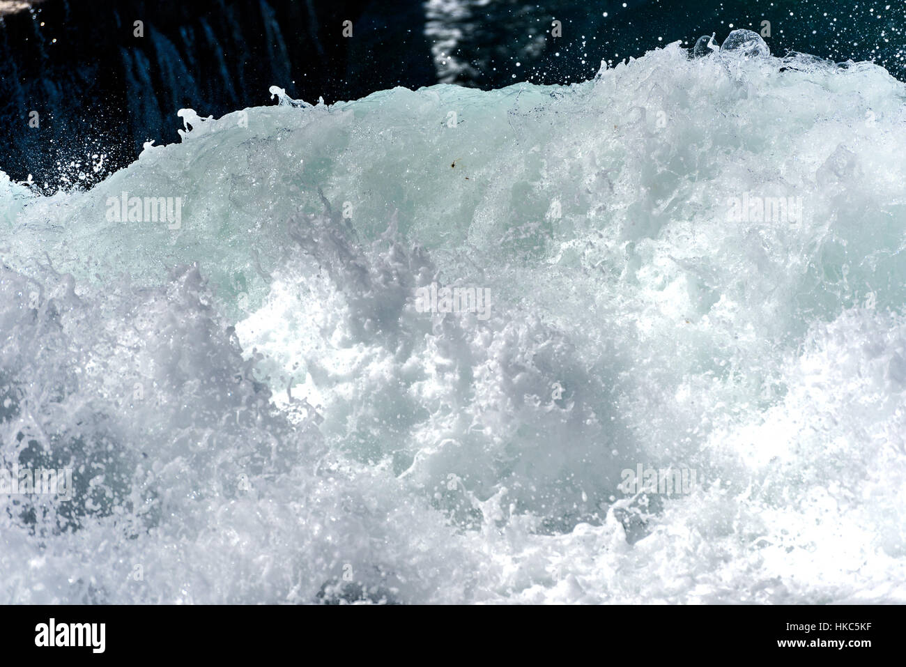 Sea foam of the waves crushing into the shore texture. Wild powerful waves are splashing and forming foam. Stock Photo