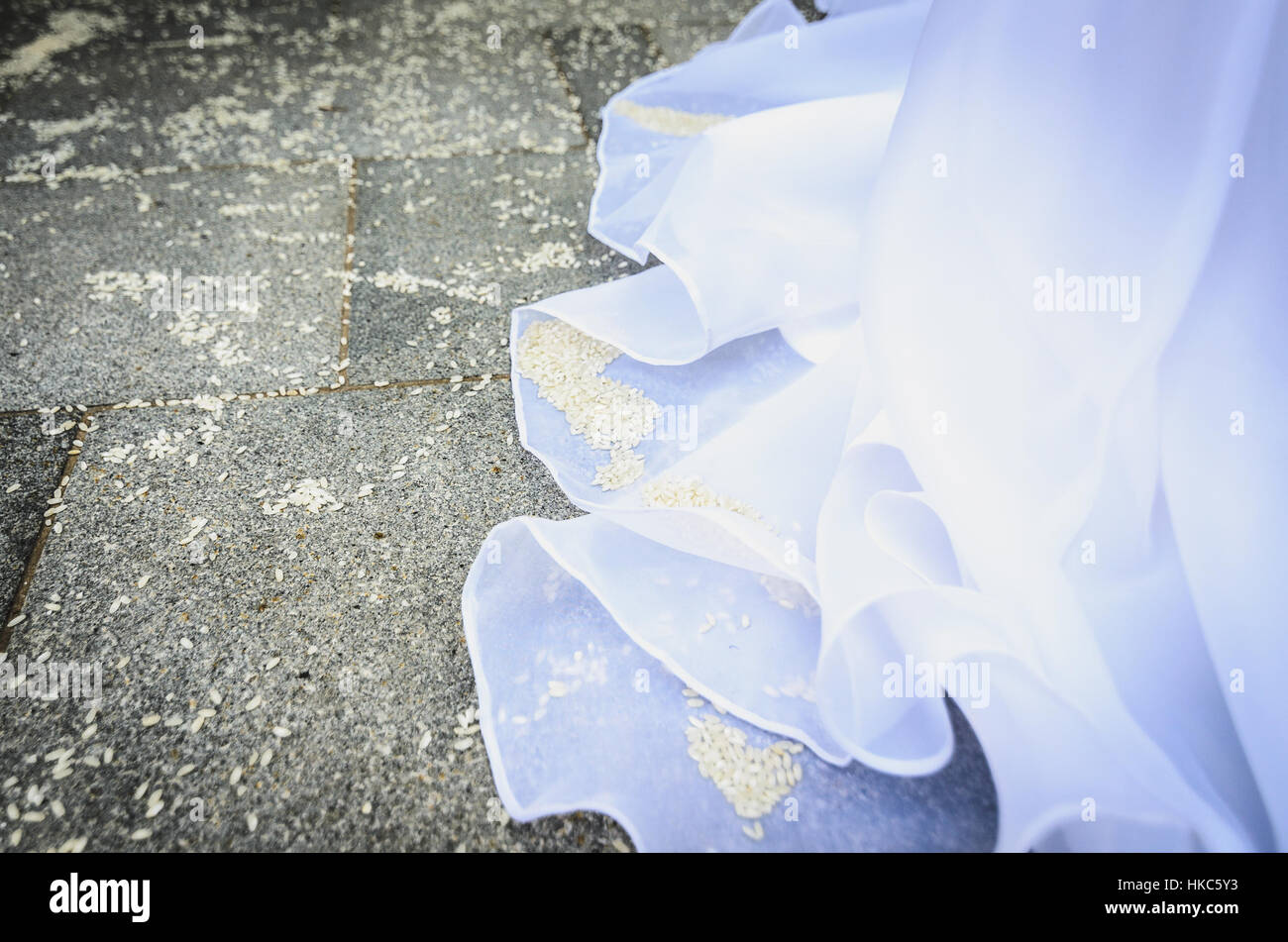 Detail of brides wedding dress with rice on the floor. Pavement full of