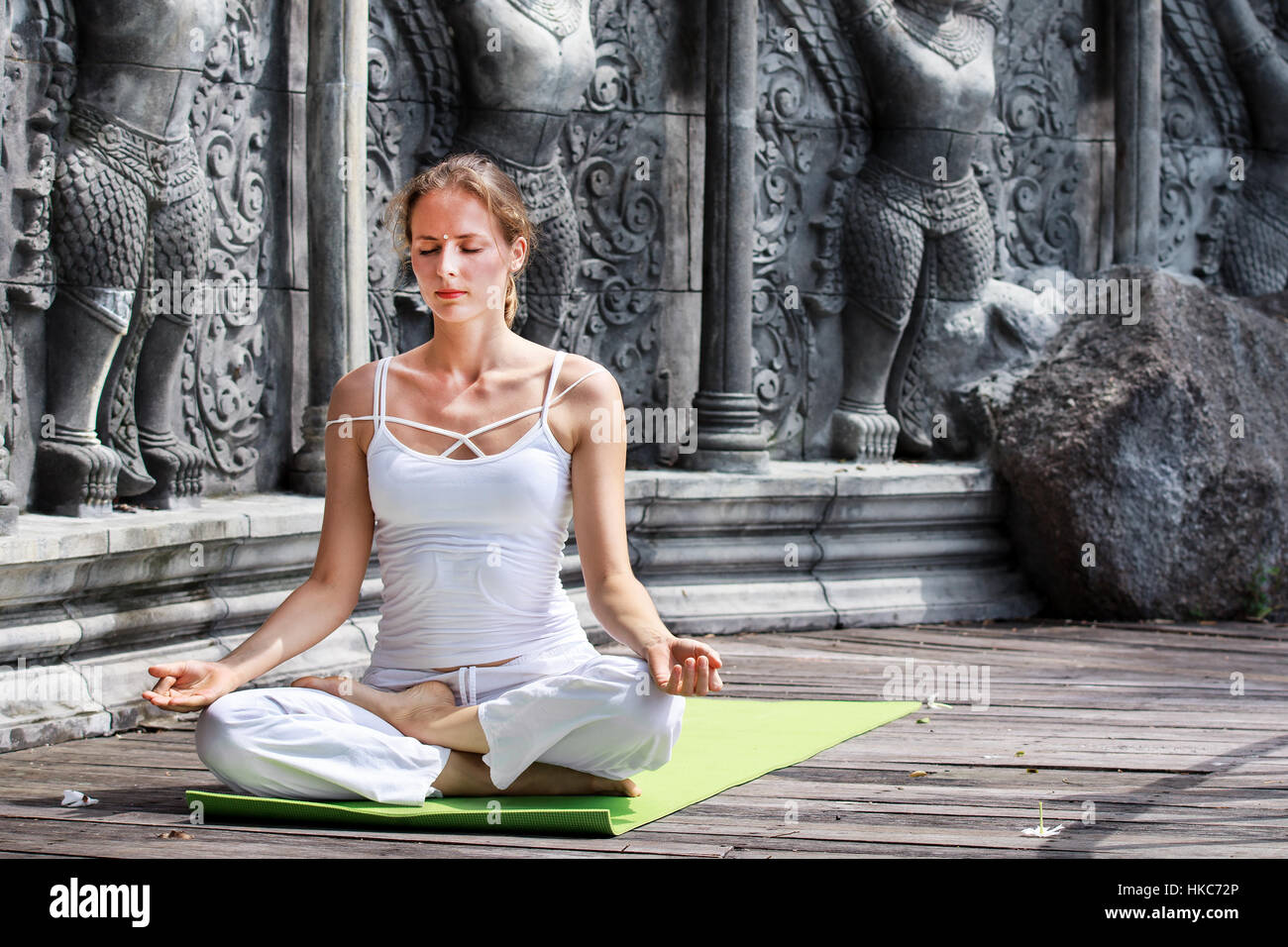Young woman doing yoga in abandoned temple on wooden platform. Practicing in Thailand Stock Photo