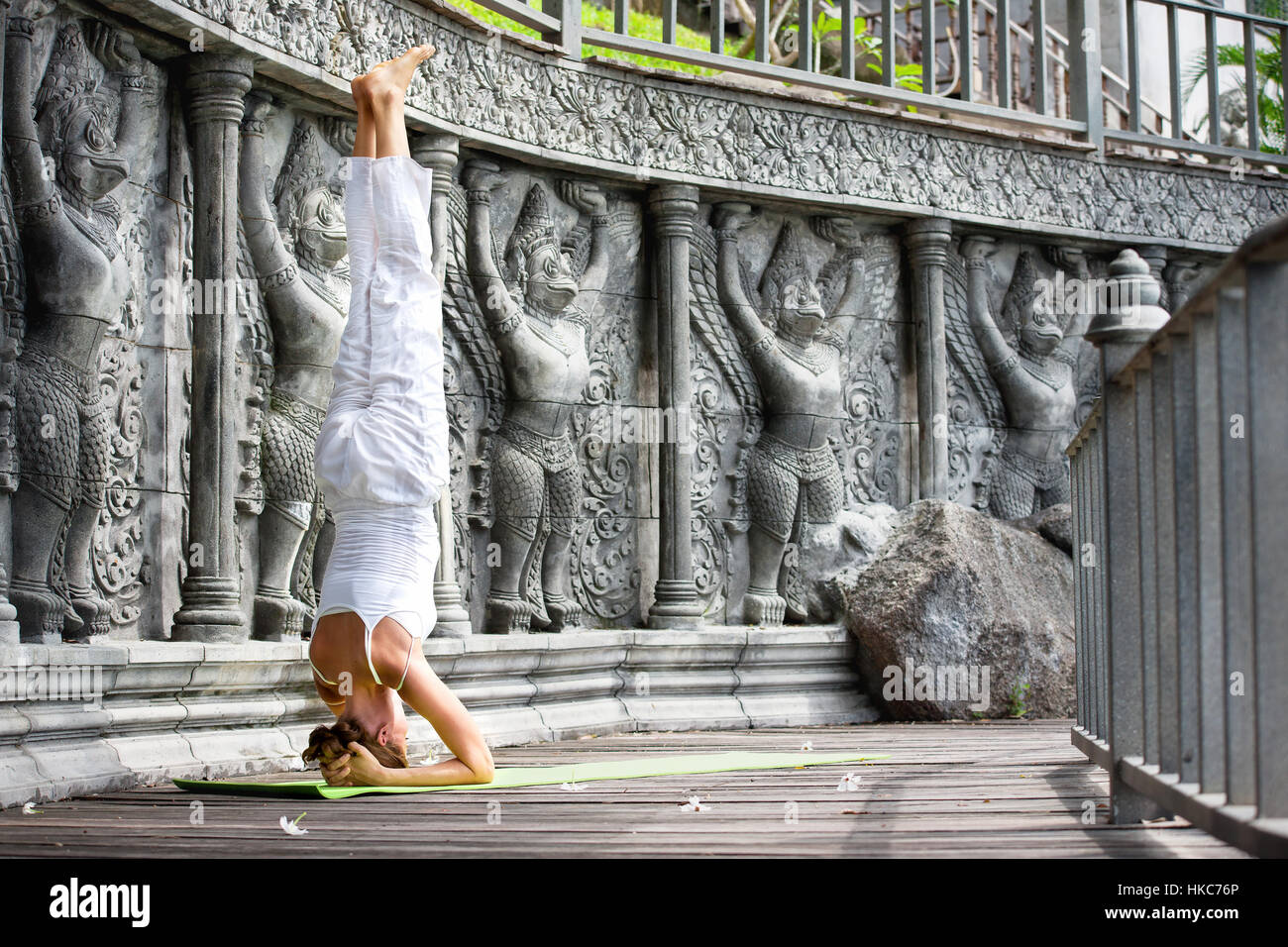 Young woman doing yoga in abandoned temple on wooden platform. Practicing in Thailand Stock Photo