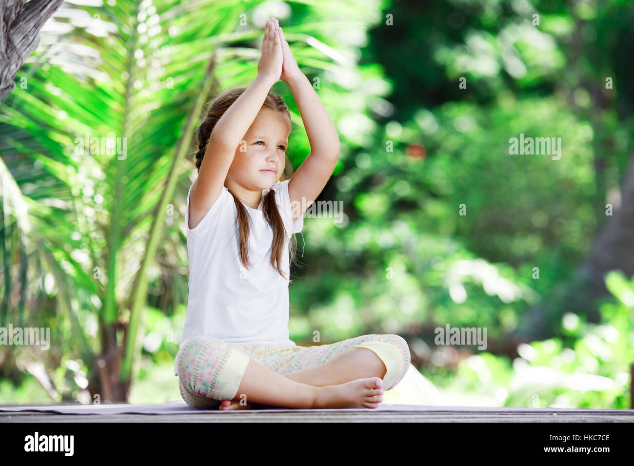 Child doing exercise on wooden platform outdoors. Healthy lifestyle. Yoga girl Stock Photo