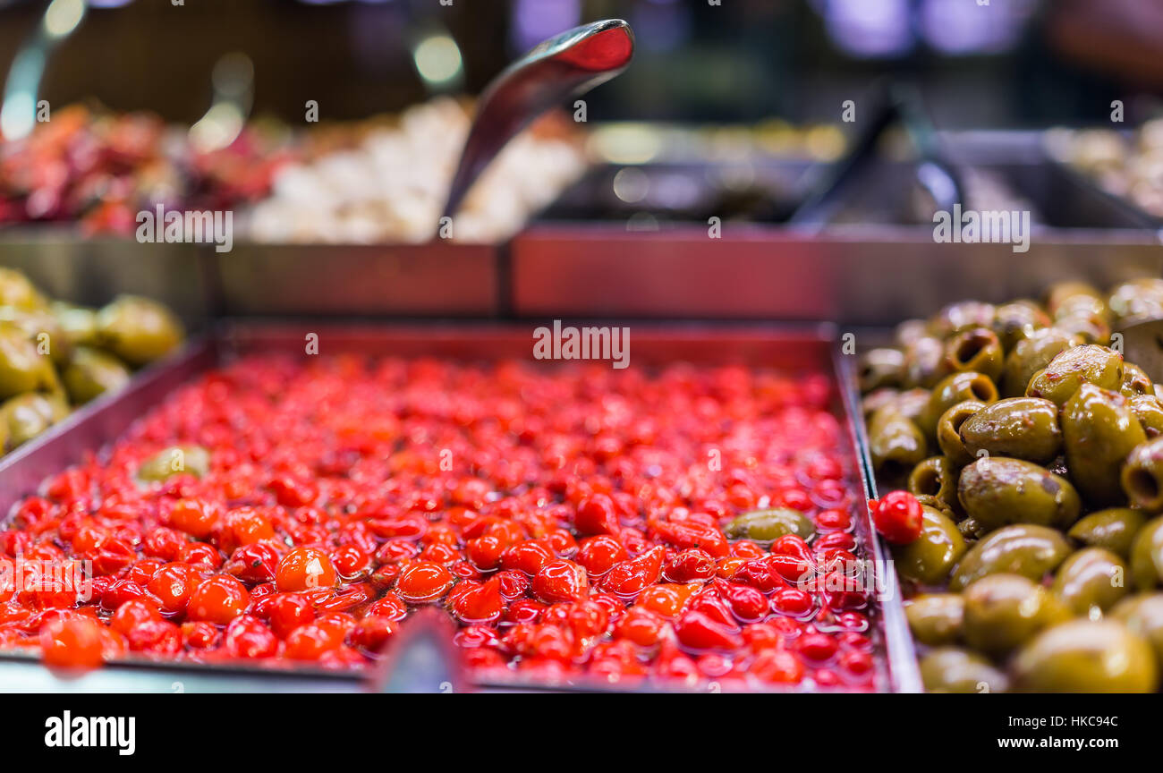Marinated small red peppers in olive bar macro closeup showing detail