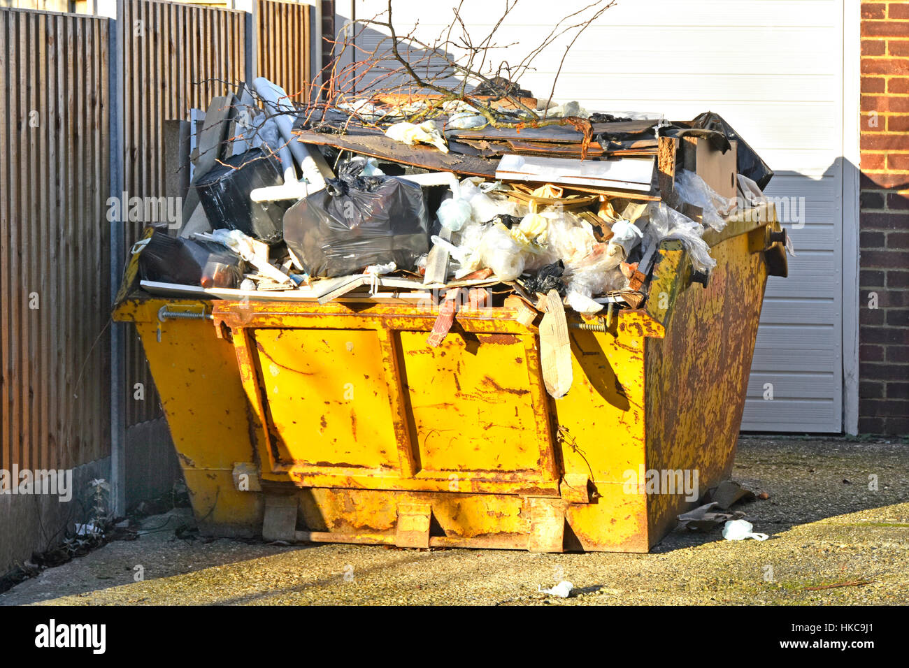 Full UK skip bin rubbish uk waste management logistics garbage trash overflowing awaiting moving to landfill from domestic property after clearout Stock Photo