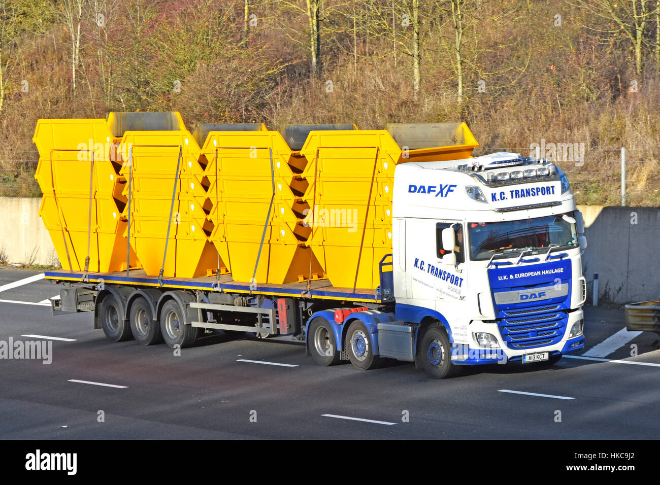 Haulage contractor HGV lorry and articulated trailer loaded with recently manufactured new rubbish skips driving along UK motorway  england, uk, Stock Photo
